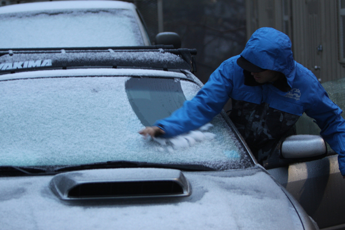 Early morning groomer wiping the snow off his windsheild.